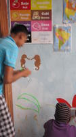 A boy paints seahorses for the mural at the new library, El Plátano, Panama 