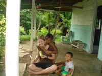 Girl hugs Rachel Teter while she is carving a totuma, or calabash gourd, El Plátano, Panama
