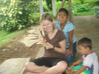 Children posing outside with Rachel Teter who is carving a totuma, or calabash gourd, in El Plátano, Panama